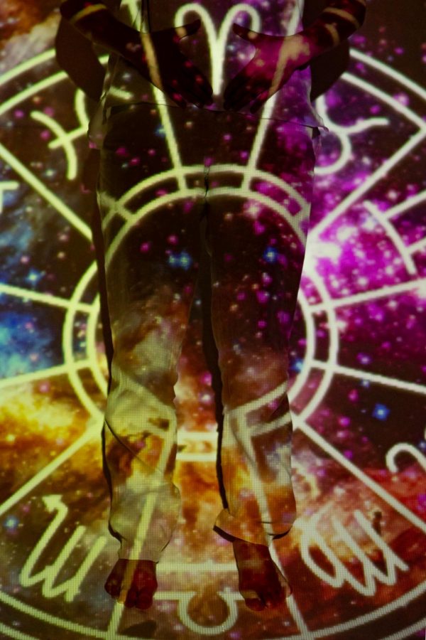 A vivid astral background is projected onto a person's silhouette, creating a cosmic and mystic visual effect.